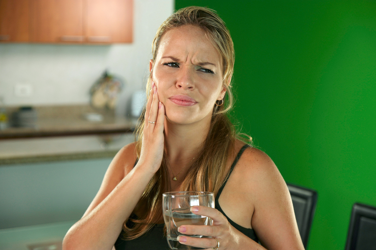 Young woman with toothache drinking cold water